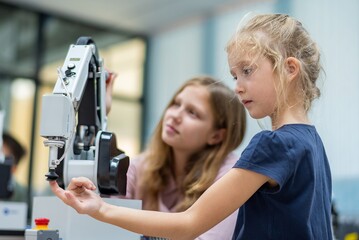 Kid female teen child enjoy Machine Learning Robot arm is Moving Under Control robot at technology...