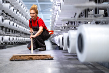 Female worker cleaning floor with broom. Keeping factory neat and clean.