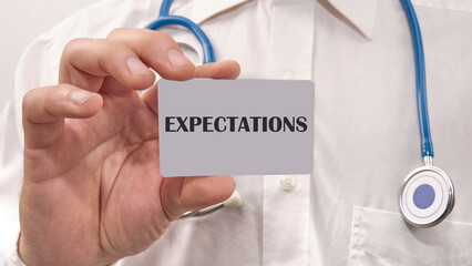 Word Expectations written on the card in the hand of a man in a white shirt