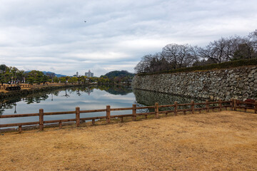 Pond with bridge at entrance of famous Unesco Word Heritage site Himeji-jo castle on a cloudy gray winter day. Photo taken February 1st, 2024, Himeji, Japan.