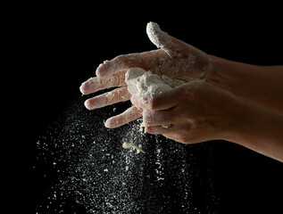 hands knead dough on a black background.