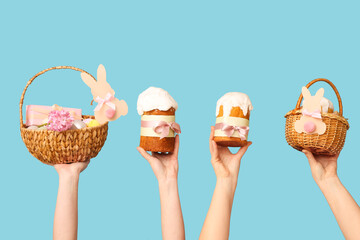 Female hands holding Easter cakes with baskets on blue background