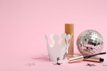 Paper crown with makeup cosmetic products and disco ball on pink background. Prom concept