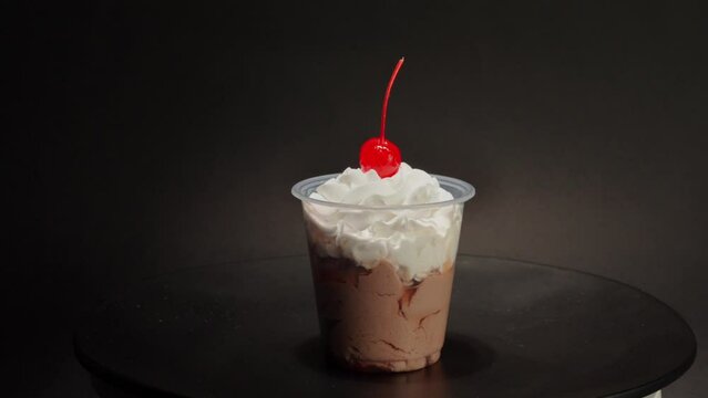 Chocolate cream cup parfait cherry on top spinning in turntable with black background