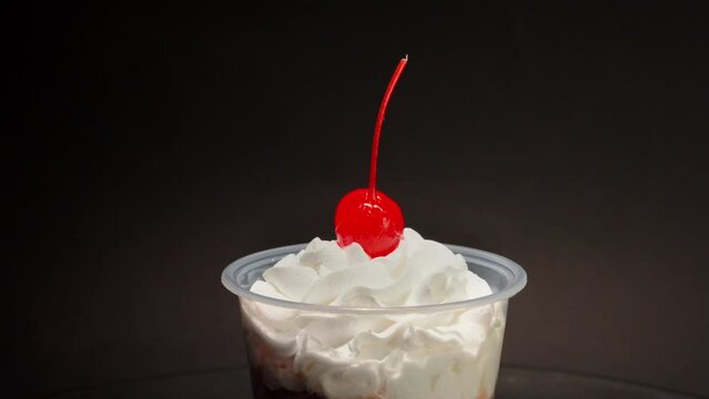 close up detail shot Chocolate cream cup parfait cherry on top spinning in turntable with black background copa nevada
