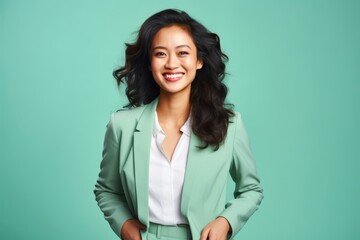 A successful East Asian businesswoman in her late 30s, against a gentle mint green background, flashing a radiant smile