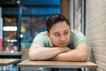 Peaceful Contemplation, young Asian man alone in a Modern Café