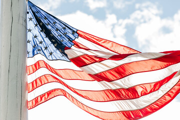 Backlit American flag on pole blowing in wind