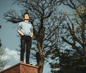 Fototapeta premium Portrait of adolescent in casual clothes at sky and trees background