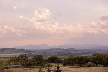 Pastel sunset over rolling hills and distant mountains