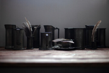 Pewter mugs and feathers on a table