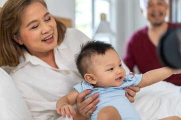 Moment of love intergenerational family portrait that and affection. A grandmother, comfortably reclining, play with cheerful baby and young girl playfully, mother, father, love across generations