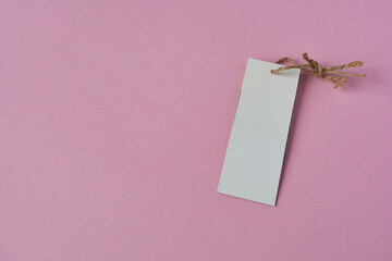 Blank clothes tag on pink background. Mockup, template with blank rectangular card for price or...