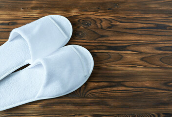 White slippers on wooden background. Top view with copy space.