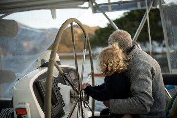 yacht steering wheel on a boat, captin steers the vessel with grandchild in australia