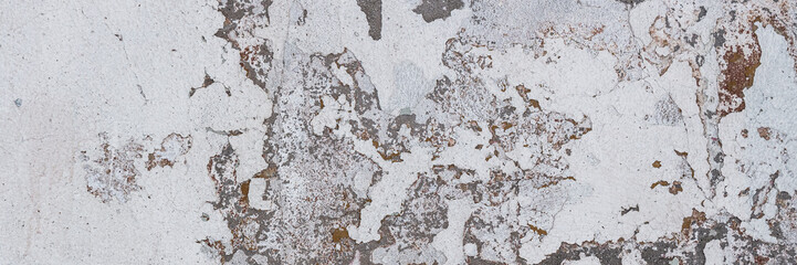 Vintage wall texture. Rough surface of the plastered concrete wall of the building. A pattern with many cracks and old faded peeling paint. Wide panoramic texture for background and design.