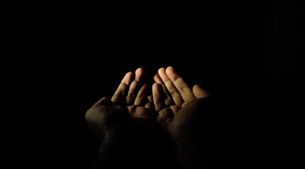 Closeup of hand pray or beg gesture isolated on night black background with copy space. Adult...