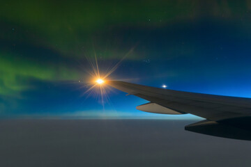 View of the northern lights (aurora) from a flying airplane. Beautiful night aerial landscape. View of an airplane wing. Travel and aviation tourism. Flight on a passenger airliner in the polar region