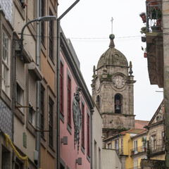 Fototapeta na wymiar An old, stone clock tower, seen amoungst the old city streets of Porto, Portugal