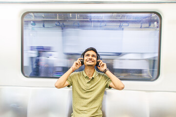 Portrait of young Indian man passenger traveling and using his smartphone in the metro or subway train. Metro and Public transportation concept. Bengaluru, India.