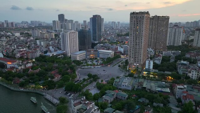 Buildings and traffic circle in city of Hanoi, Vietnam evening near lake - Aerial 4K drone footage of cars on road in Hanoi West Lake Neighborhood (Tay Ho).