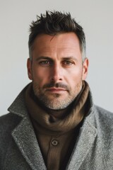 Portrait of handsome man in coat looking at camera on grey background