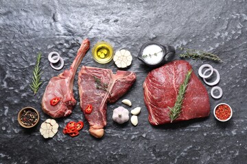 Fresh raw beef cuts and different spices on grey textured table, flat lay