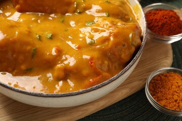 Tasty chicken curry and spices on green place mat, closeup