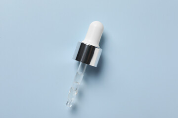 Pipette with moisturizing serum on light grey background, top view. Space for text