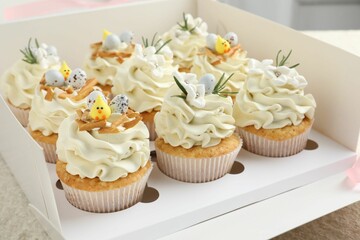 Tasty Easter cupcakes with vanilla cream in box on table, closeup