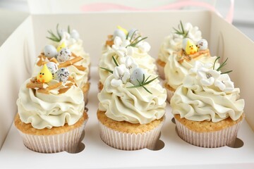 Tasty Easter cupcakes with vanilla cream in box, closeup