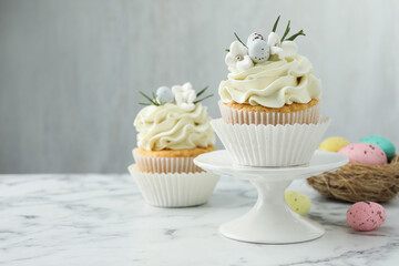 Tasty Easter cupcakes with vanilla cream on white marble table, space for text