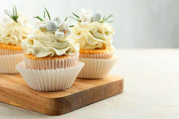Tasty Easter cupcakes with vanilla cream on gray table, space for text