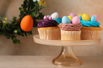 Tasty cupcakes with Easter decor on wooden table. Space for text