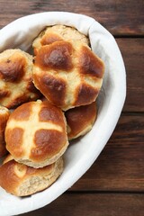 Hot cross buns in basket on wooden table, top view