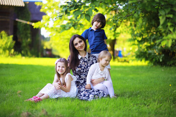 Obraz premium Young large family on a summer morning walk. Beautiful mother with children is playing in the park.