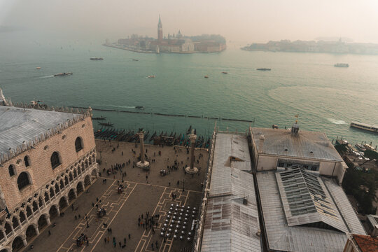 View from Campanile di San Marco: overlooking Bacino di San Marco, with gondolas and boats moored to wooden posts. Across the Grand Canal, San Giorgio Maggiore and Giudecca islands fade into the fog.