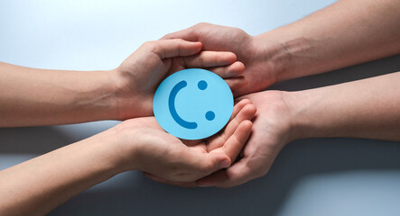 paper cut smiley face in hands on light blue background. positive thinking, mental health, assessment, world mental health day concept