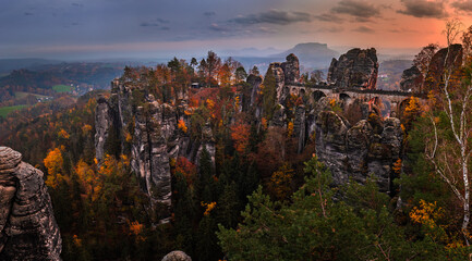 Saxon, Germany - Panoramic view of the Bastei bridge with a sunny autumn sunset with colorful foliage and sky. Bastei is famous for the beautiful rock formation in Saxon Switzerland National Park