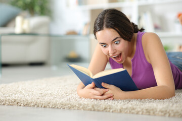 Amazed woman reading a paper book on a carpet