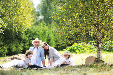 Happy family with children having picnic in park, parents with kids sitting on garden grass and...