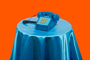 Vintage style telephone on table against orange background