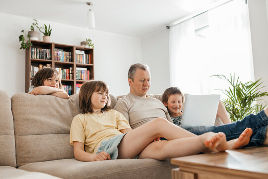 Father watching movie with children on laptop at home