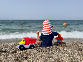 Little boy playing sitting on the sand at the beach
