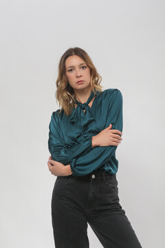 Serie of studio photos of young female model wearing green silk satin blouse and black trousers
