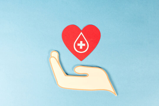 A hand holding red drops of blood, blood donation concept.