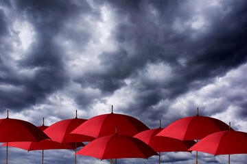 open red umbrellas under a dramatic cloudy and stormy sky