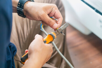 Technician man cutting electrical wires with pliers for installing new air conditioning, repair service, and install new air conditioner concepts