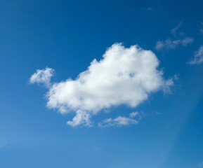 Single white fluffy cumulus cloud in the blue summer sky
