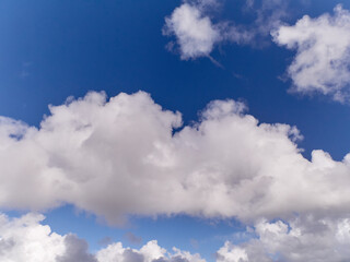 White fluffy cumulus clouds in the summer sky, natural clouds background